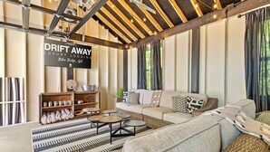 En hyggelig lounge med sofa, runde sofaborde og en dekorativ reol. Et skilt siger "DRIFT AWAY LUXURY LODGING Blue Ridge, GA".