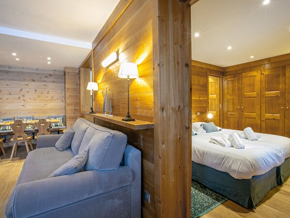 Una habitación acogedora con sofá, cama, paredes de madera y un escritorio con sillas.