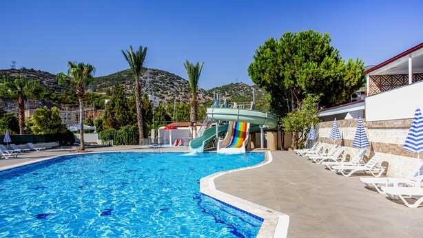Una piscina amb tobogan, gandules i ombrel·les.