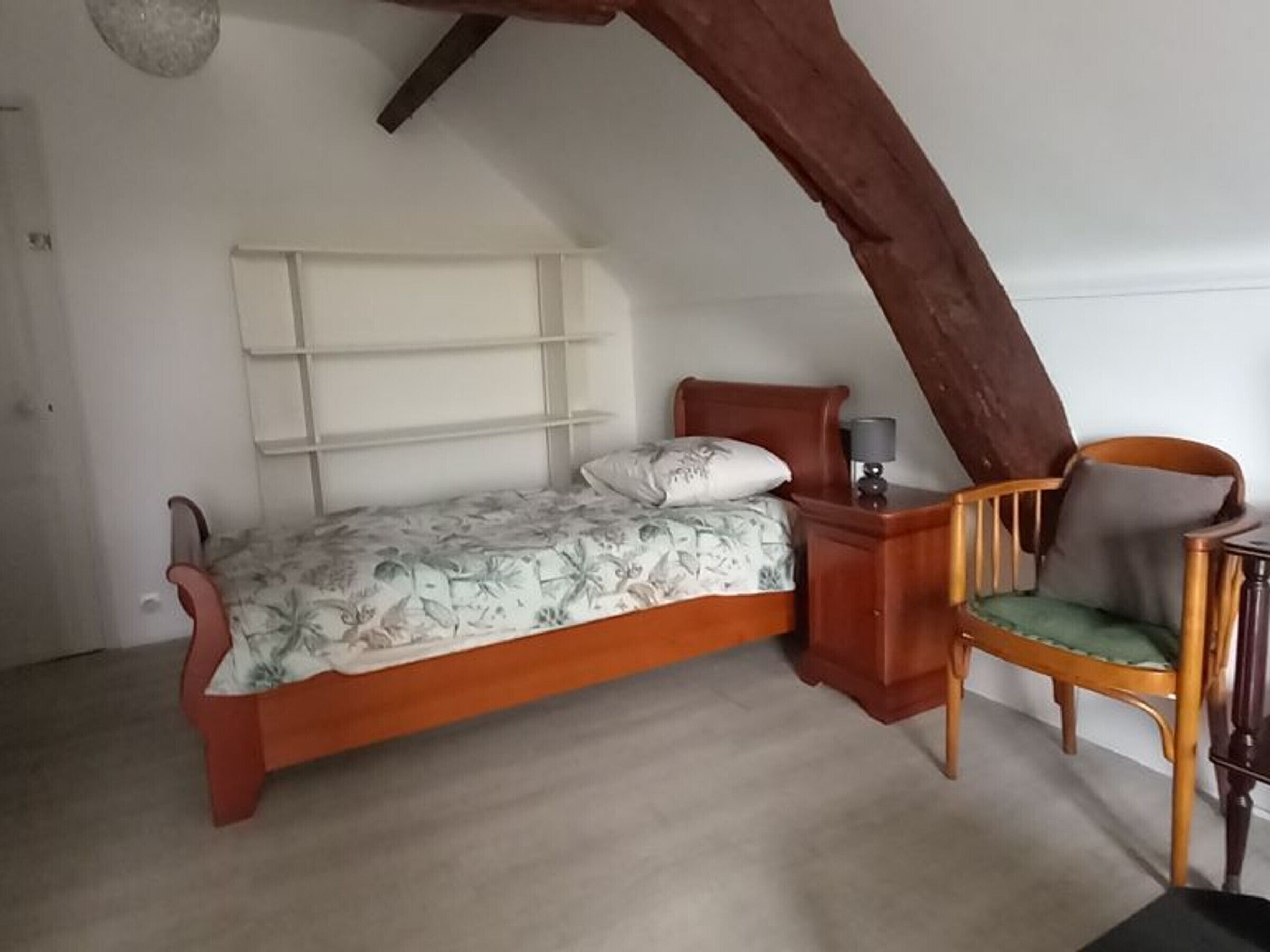 A bedroom with a single bed, a wooden chair, and a nightstand.