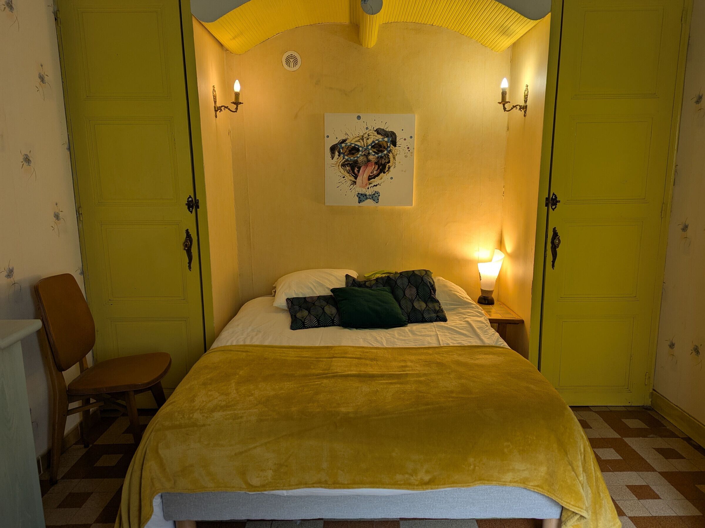 A room with a bed, a chair, and two doors.