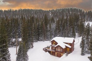 Una cabaña de madera rodeada de árboles cubiertos de nieve.