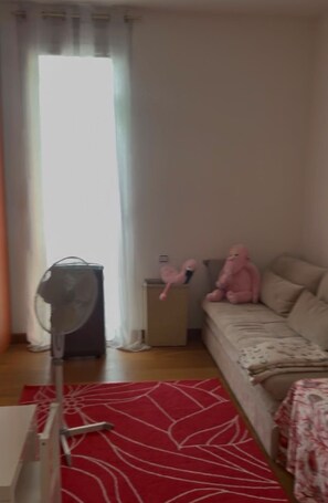 A bedroom with a bed, a fan, a red patterned rug, and a window with curtains. - Elizaveta apartment with lake view and terrace (Oggebbio)