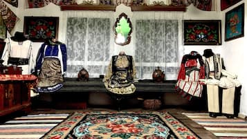 A traditional room with a patterned carpet, a wooden bench, and a variety of cultural artifacts including clothing and decorative items.