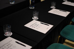 Una mesa de conferencias con placas de identificación y bolígrafos, mostrando una disposición formal para una reunión.