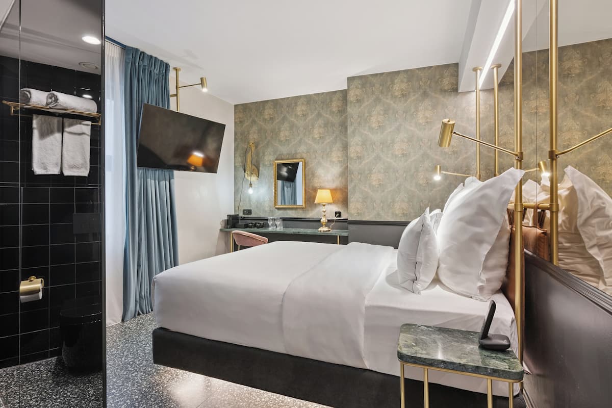 A modern hotel room with a large bed, a desk, a mirror, and a TV.