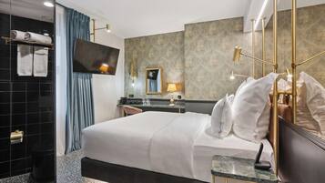 Una habitación de hotel moderna con una cama grande, un escritorio, un espejo y un televisor.