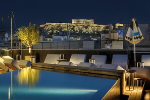 A rooftop pool area with lounge chairs, a tree, and a view of ancient ruins. - Skylark, Aluma Hotel & Resort (Athens)