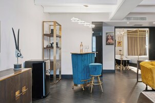 Een moderne woonkamer met een blauwe bar, een gele bank en een boekenkast.
