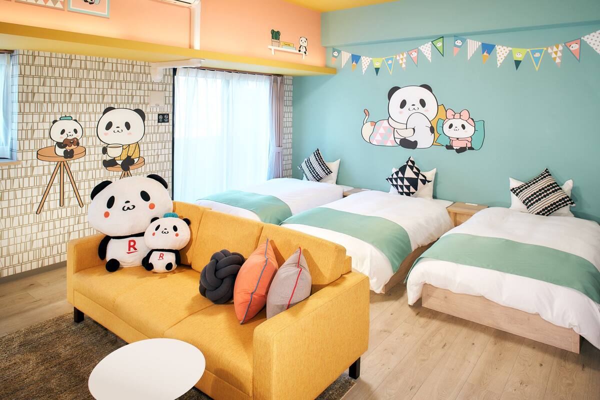 Een kamer met twee bedden, een slaapbank en panda-decoraties.