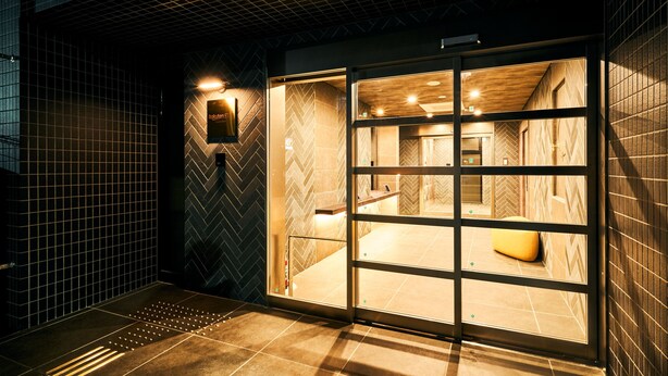 A modern bathroom with a herringbone tile pattern, a glass partition, and a wooden bench. - Rakuten Stay Fukuoka - Yakuin (Fukuoka)