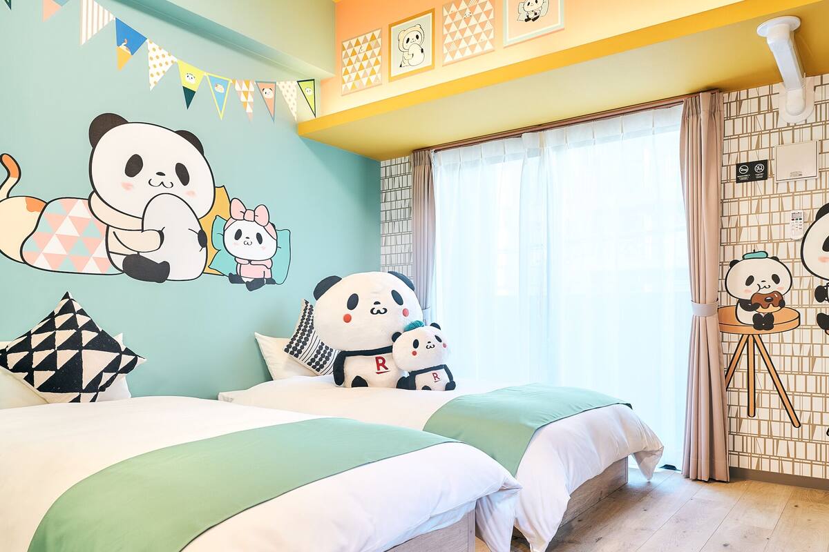 Een kamer met twee bedden, panda-decoratie op de muur en een raam met gordijnen.