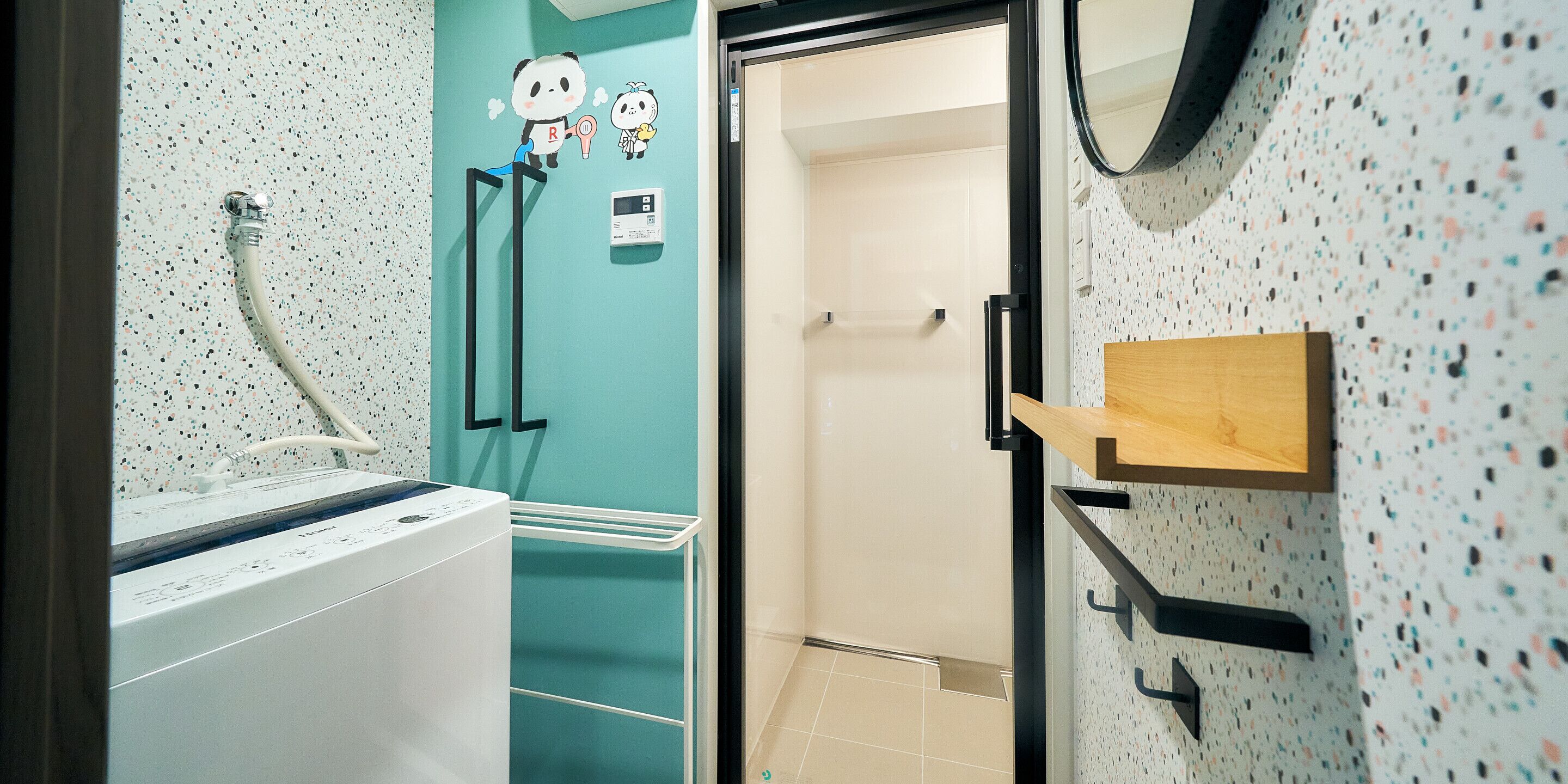 A bathroom with a washing machine, a towel rack, a shower, and a mirror.
