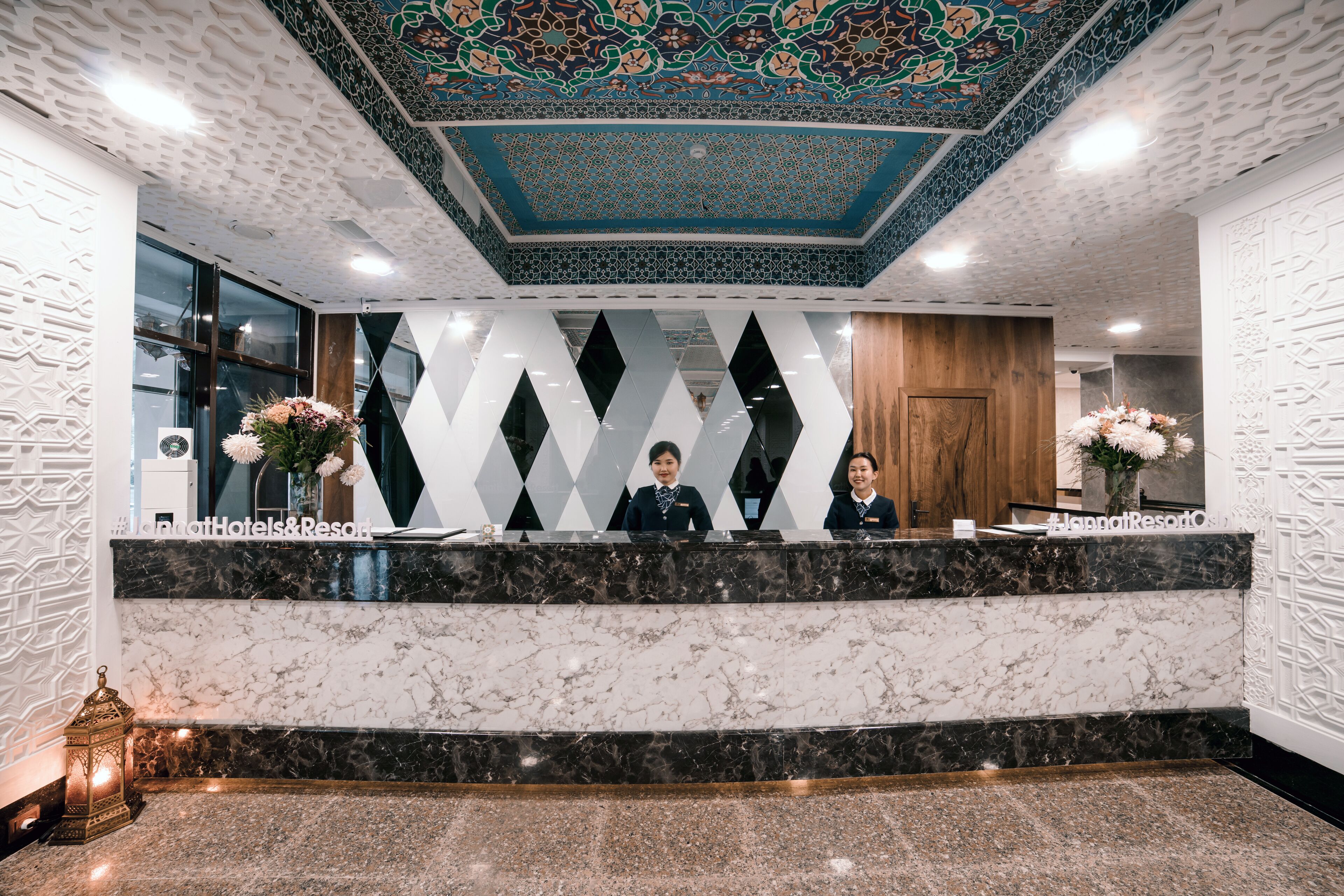 Una zona de recepción de hotel con mostradores de mármol, un techo decorativo y un diseño moderno.