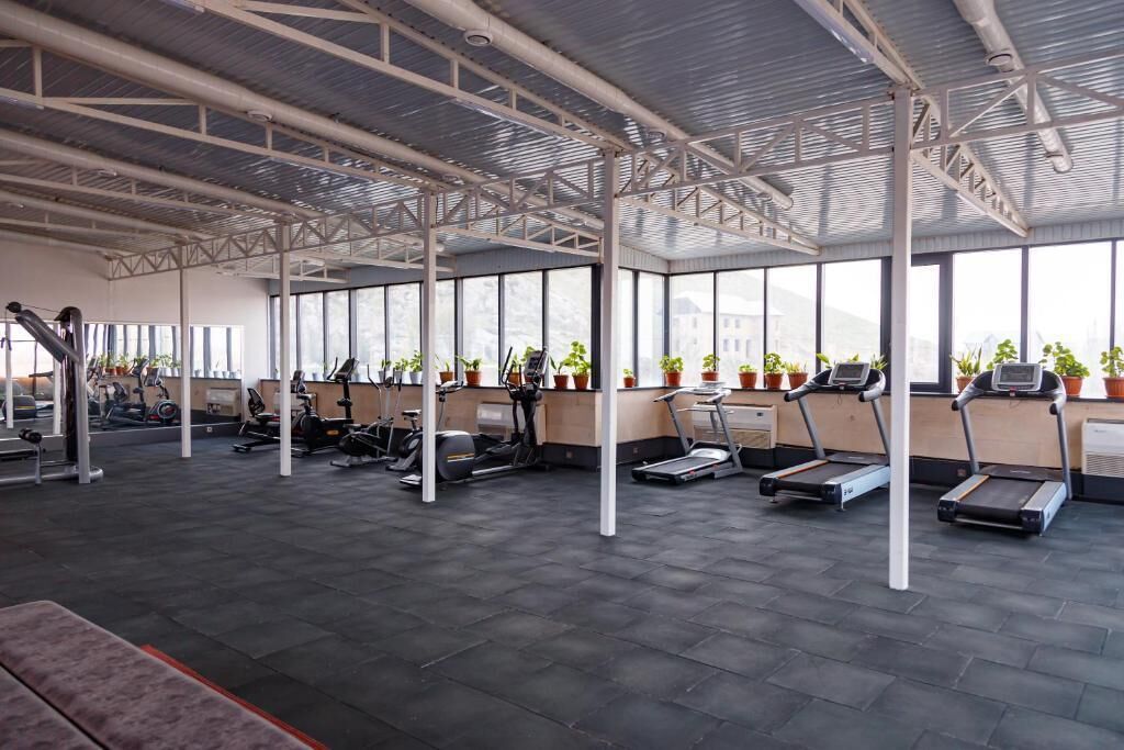 A gym with treadmills, elliptical machines, and weight stations.