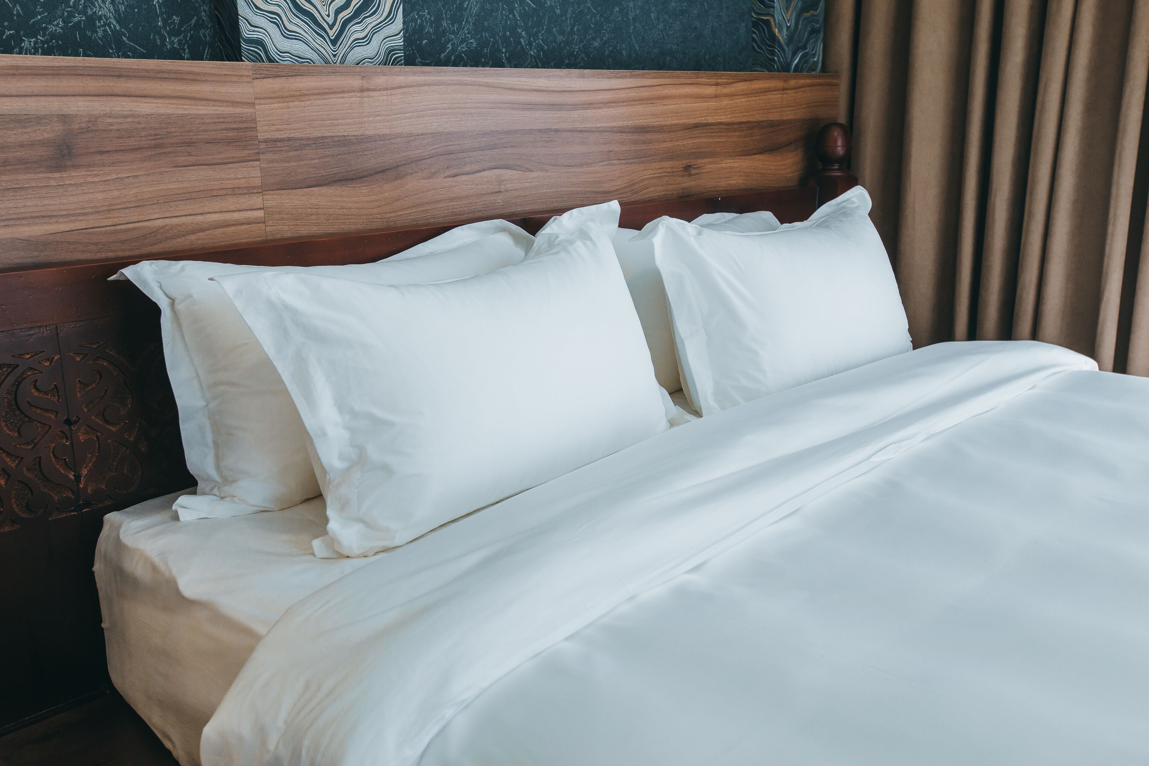 Una cama bien hecha con sábanas blancas y cabecera de madera.