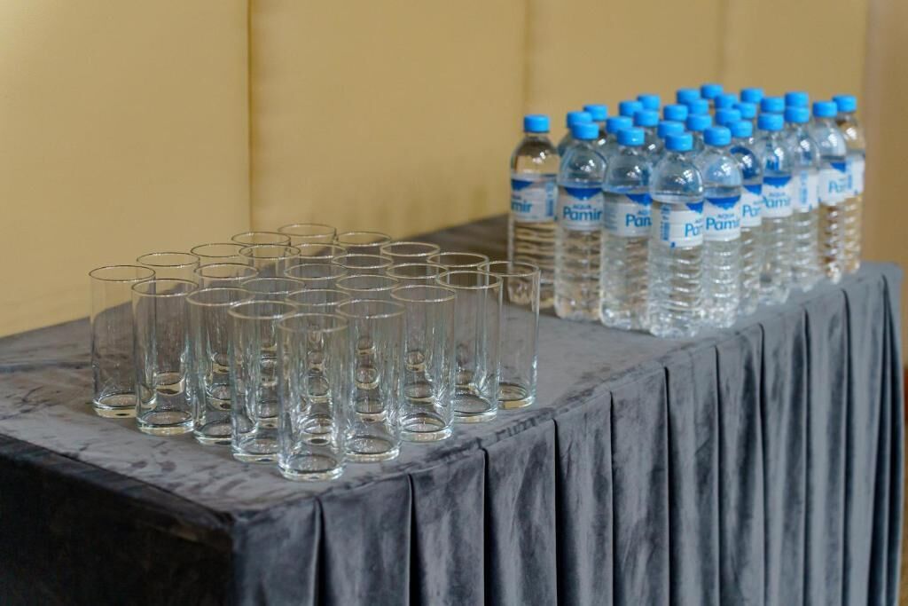 Una mesa con varios vasos vacíos y botellas de agua.