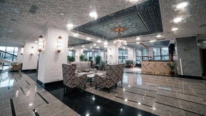 Un hall d’entrée spacieux, agrémenté de canapés à motifs, d’un comptoir de réception et d’un plafond décoratif.