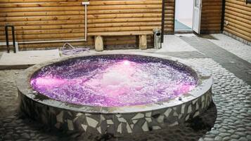 Relax in a hot tub surrounded by a serene outdoor setting.
