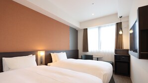 Une chambre d’hôtel avec deux lits, un bureau, une chaise, une télévision et une fenêtre avec des rideaux.