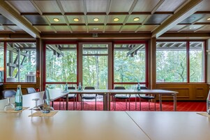 Sala de conferências com uma mesa comprida, cadeiras e um tapete vermelho.