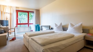 A hotel room with two beds, a desk, a chair, a TV, and a window with curtains. - Raststättenhotel Baden-Baden (Baden-Baden)