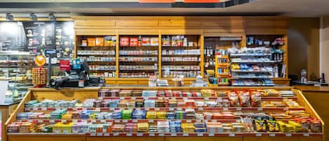 A grocery store with a deli counter, shelves stocked with snacks, and a coffee section.
