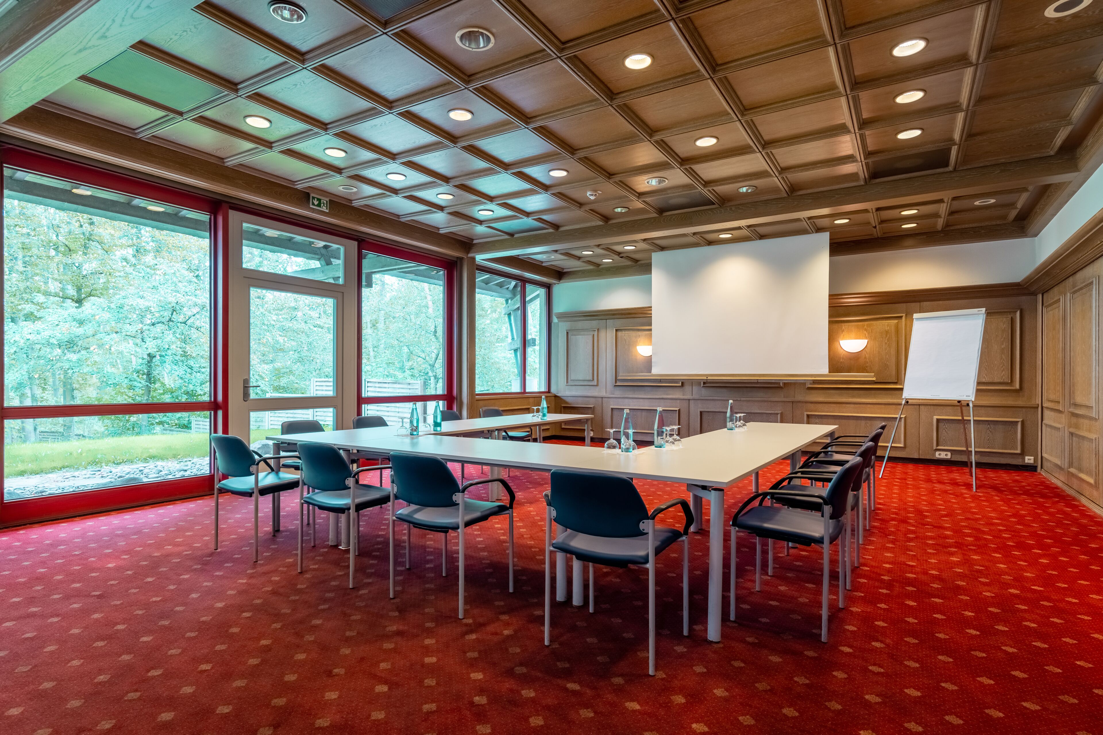Una sala de conferencias con una gran mesa, sillas, una pizarra y una pantalla de proyector.