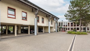 A motel with a covered parking area and a building with multiple windows and a sign. - Raststättenhotel Baden-Baden (Baden-Baden)