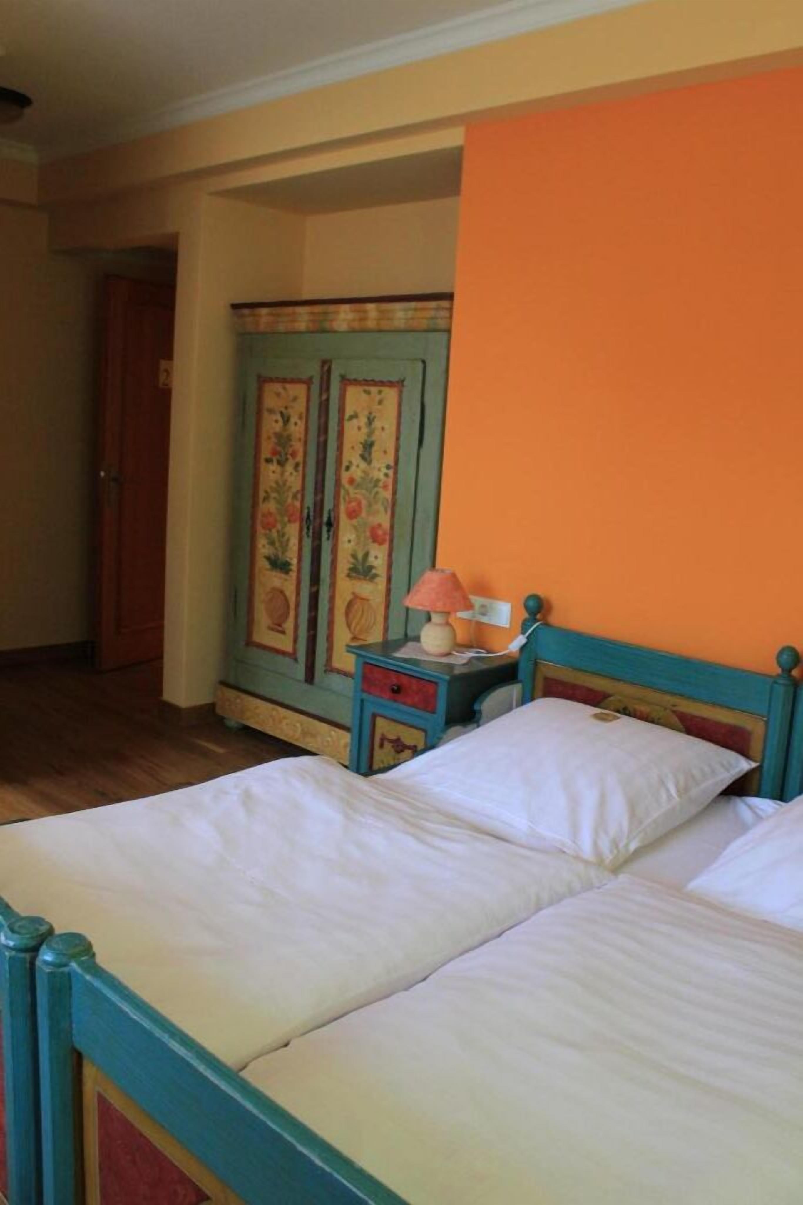 Une chambre avec deux lits, une armoire en bois et une table de chevet avec une lampe.