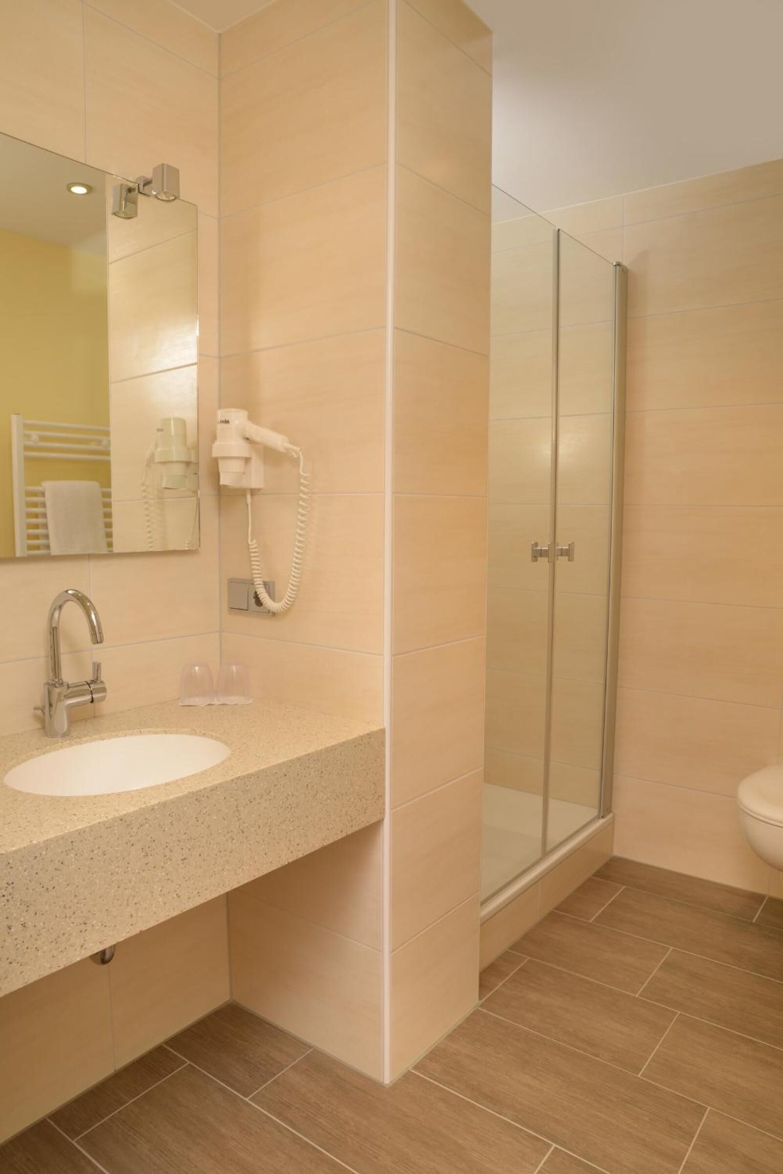 A modern bathroom with a sink, mirror, and shower.