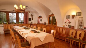 A long dining table with chairs, wooden benches, and a chandelier. - Landgasthof Haueis (Marktleugast)