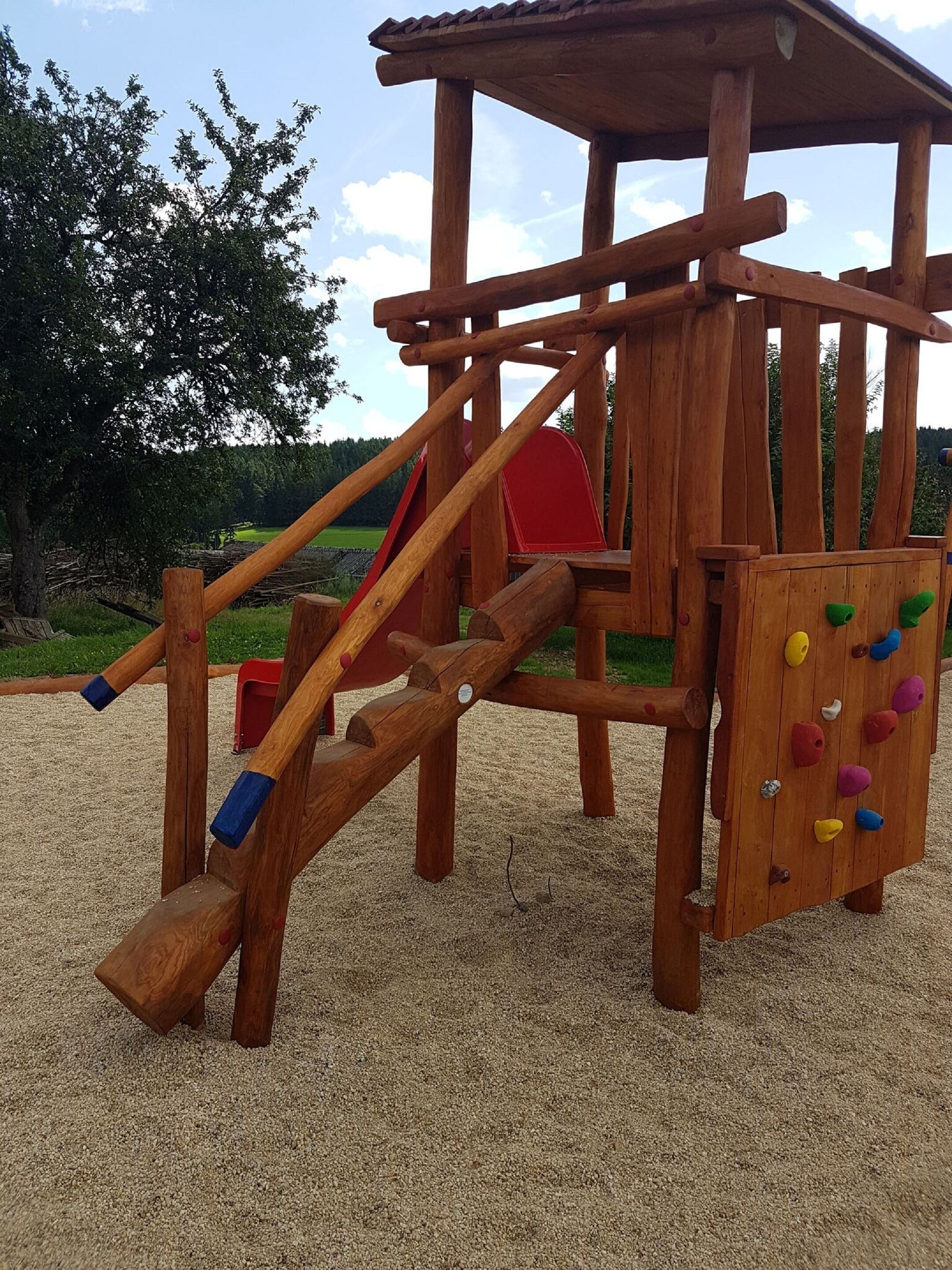 Una estructura de juegos de madera con puntos de escalada y un tobogán.