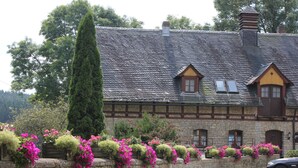 A stone building with a sloped roof, wooden beams, and flower boxes along the front wall. - Landgasthof Haueis (Marktleugast)