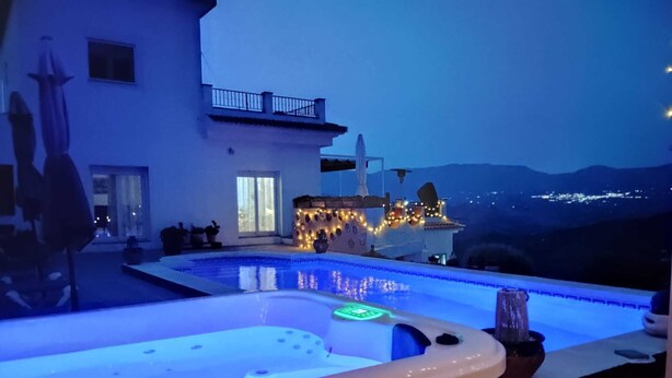 A modern pool area with a hot tub, a well-lit deck, and a view of a mountain range. - Great 2 Bedroom Apartment with wonderful views, Swimming Pool and Jacuzzi (Comares)