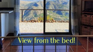 A bedroom with a large sliding glass door leading to a scenic mountain view. - Great 2 Bedroom Apartment with wonderful views, Swimming Pool and Jacuzzi (Comares)