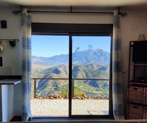 A bedroom with a large sliding glass door leading to a scenic mountain view.