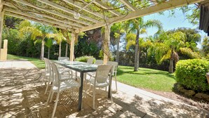 Patio esterno con pergola, un tavolo e sedie.