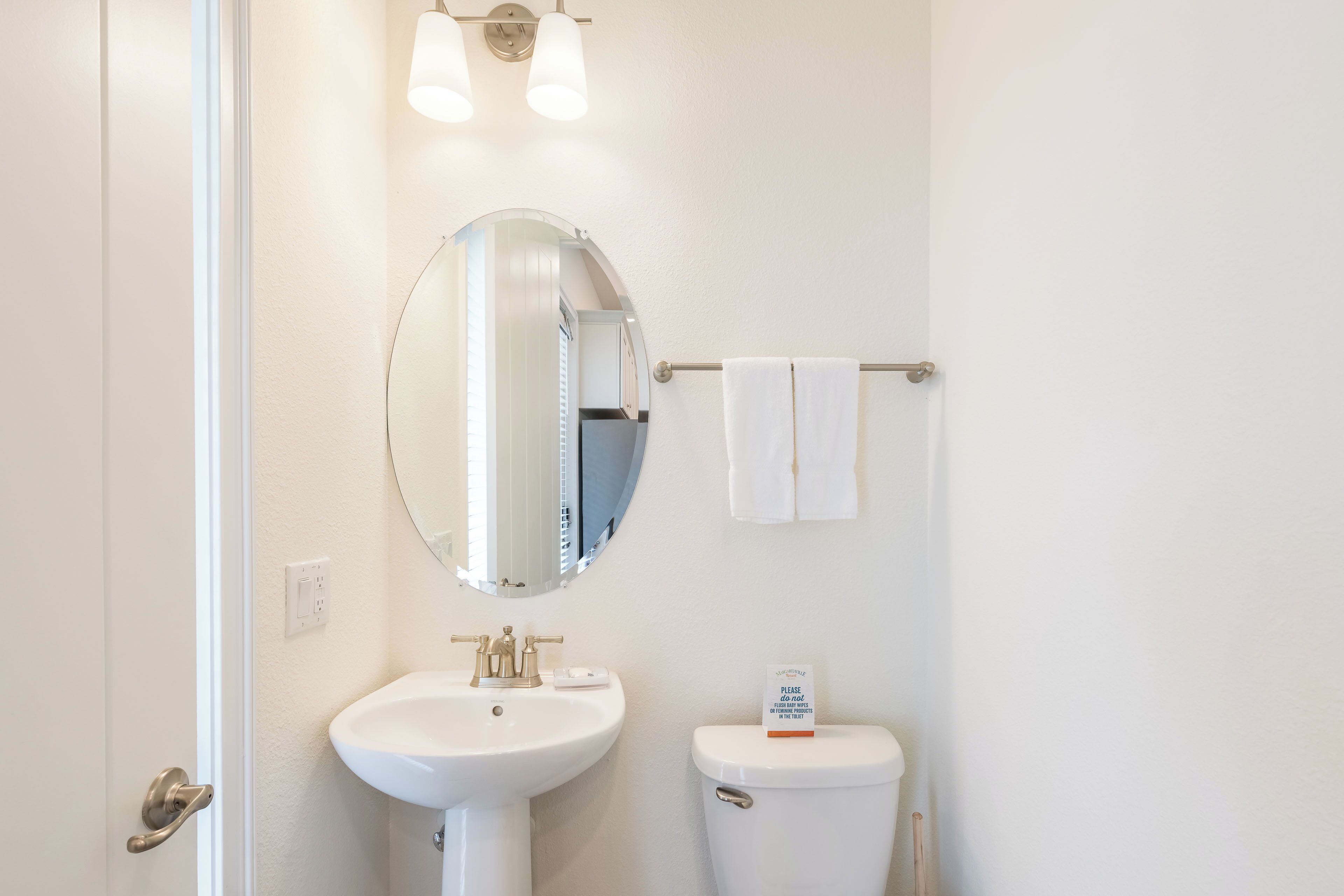 A bathroom with a white sink, a mirror, a toilet, and a towel rack.