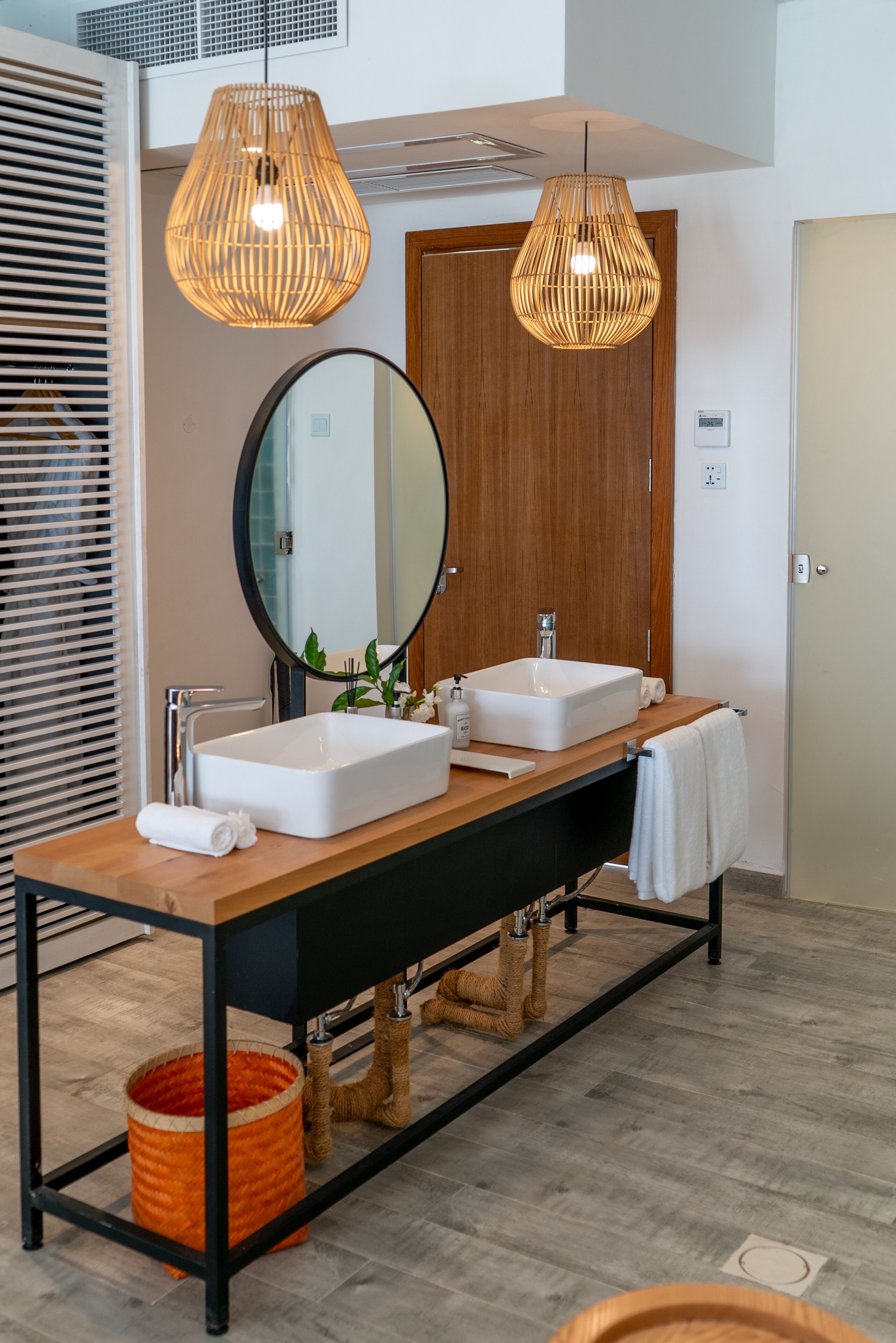 A modern bathroom with two sinks, a large mirror, and two hanging wicker light fixtures.
