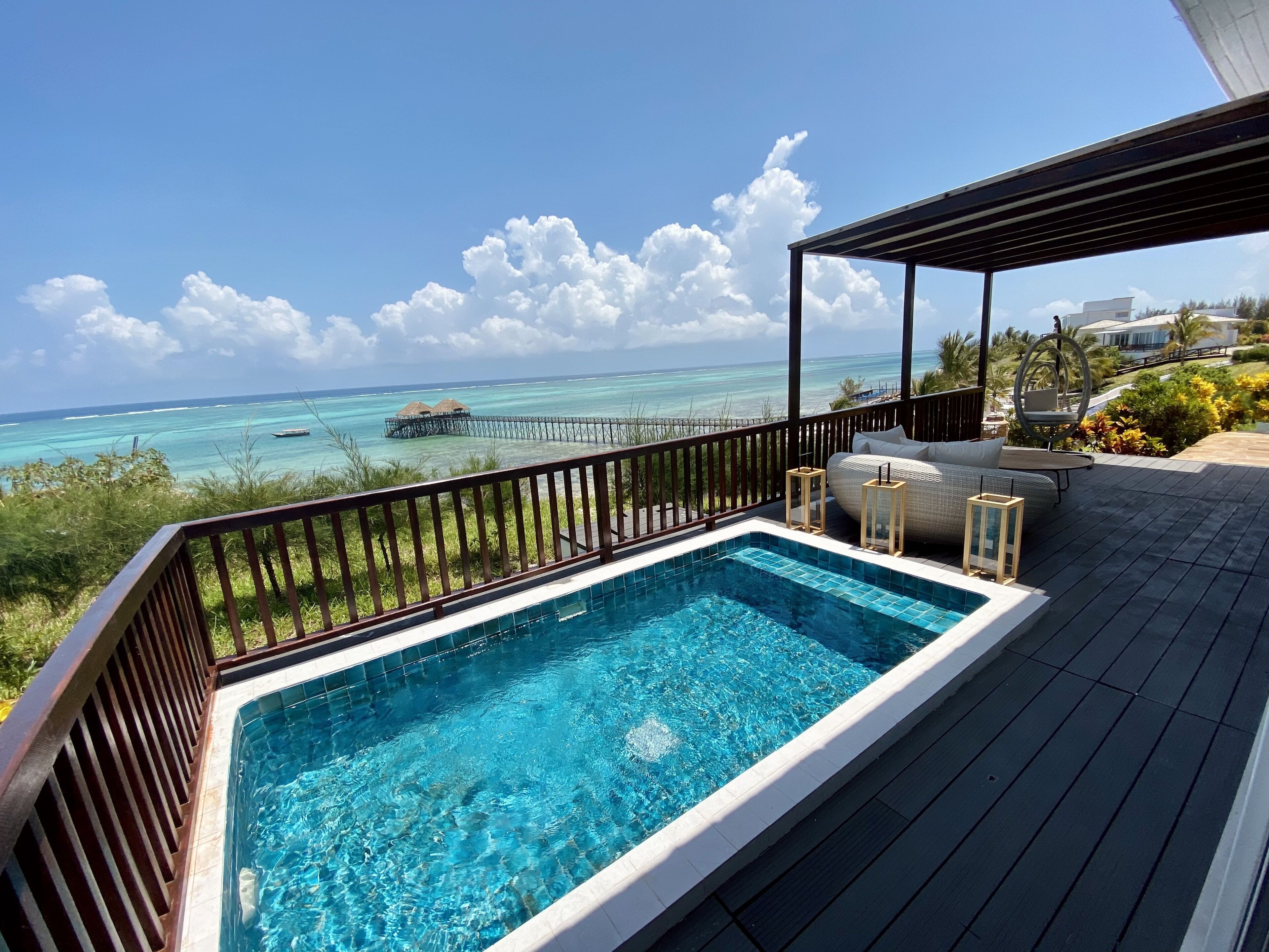A swimming pool with a view of the ocean and a wooden deck.