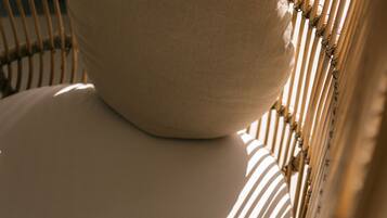A wicker chair with a cushion and a woven pillow.