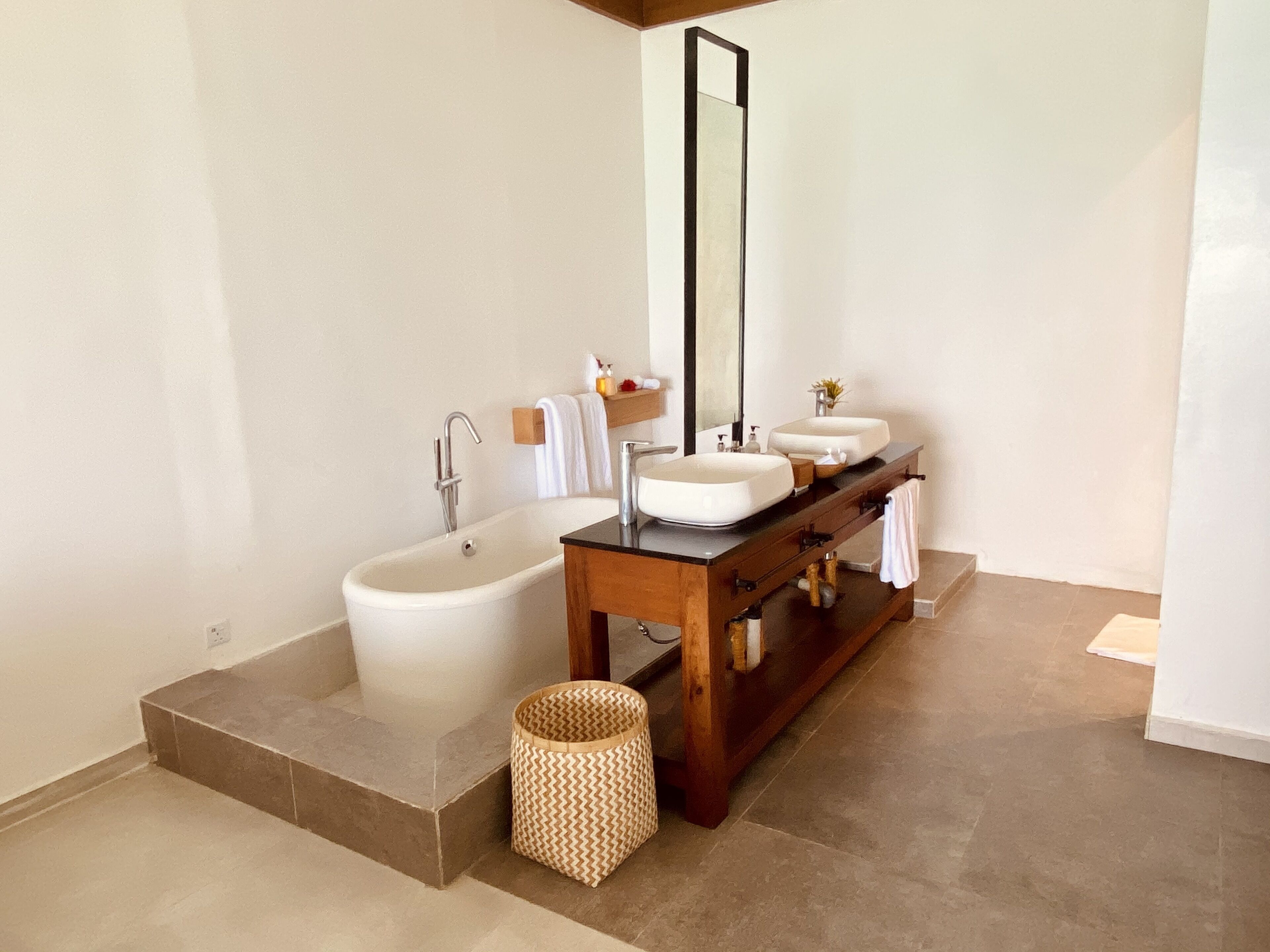 Une salle de bain moderne avec une baignoire sur pieds, un meuble-lavabo doté de deux vasques et un grand miroir.