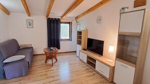 A cozy living room with a sofa, TV, and wooden cabinets. - Holiday Homes Marta (Rovinj)