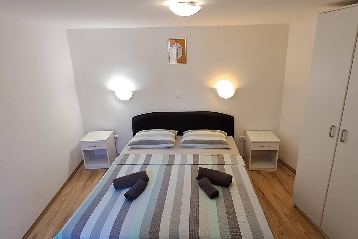 A bedroom with a bed, two bedside tables, a wardrobe, and two wall-mounted lights.