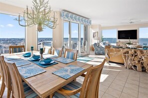 A dining area with a view of the city, a balcony with outdoor seating, and a wooden table with blue placemats.