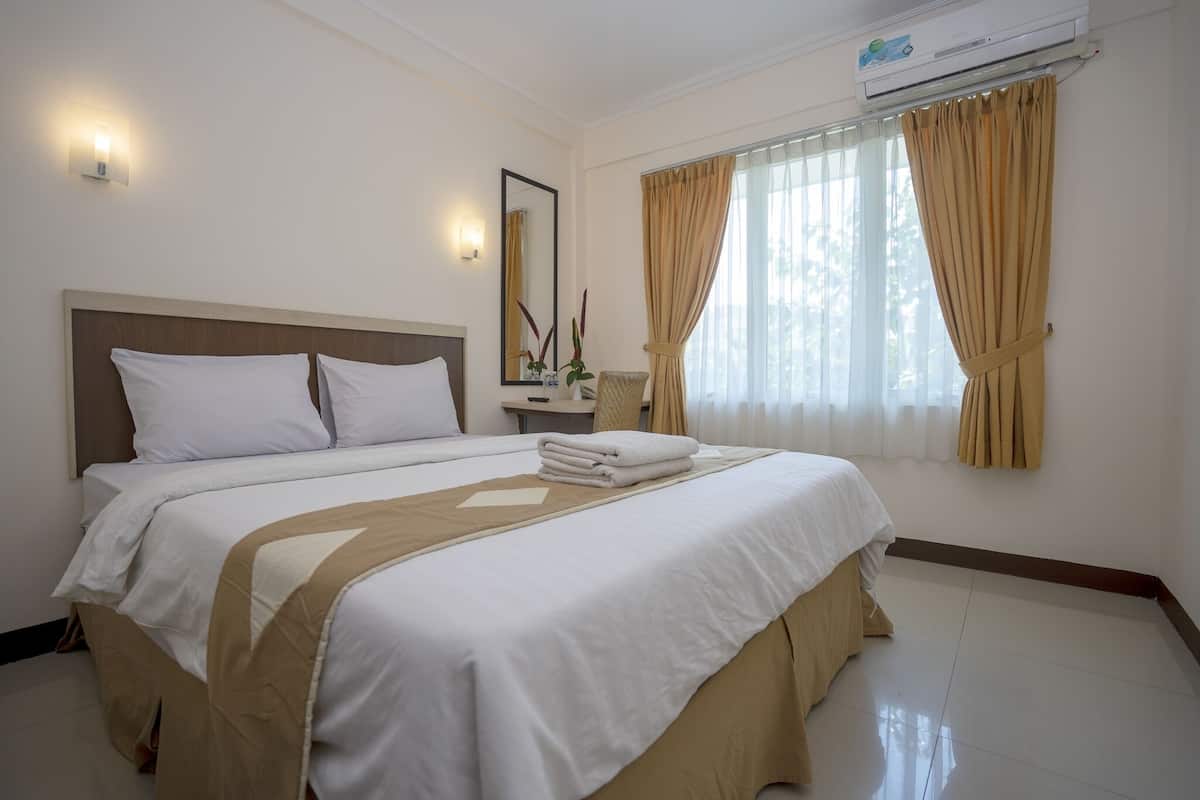 Habitación de hotel con dos camas, una mesita de noche, un espejo y una ventana con cortinas.