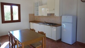 Una cocina con una mesa de comedor, sillas, estufa, armarios y un refrigerador.
