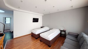 A hotel room with two single beds, a sofa, a TV, and a small bedside table. - Apartment in Bad Homburg, 2 rooms (Bad Homburg vor der Höhe)