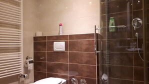 A bathroom with a toilet, a shower, and a towel rack. - Apartment in Bad Homburg, 2 rooms (Bad Homburg vor der Höhe)